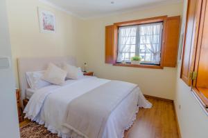 a bedroom with a white bed and a window at Araújo 111 - Traditional House in Leça do Balio