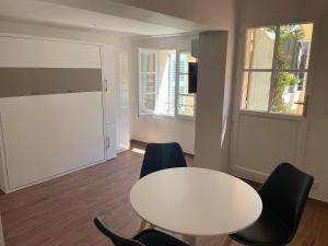 a white table and chairs in a room with a window at Saint-Tropez Centre - Grand Studio avec terrasse in Saint-Tropez +8 photos
