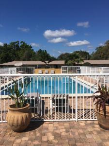 a white fence around a pool with chairs and plants at Days Inn by Wyndham Orange City/Deland in Orange City