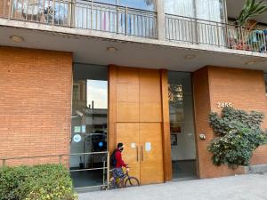 een man die met een fiets voor een gebouw loopt bij Jardines in Santiago