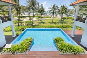 een overloopzwembad op het terras van een resort met palmbomen bij Da Nang Paradise Center My Khe Beach Resort & Spa in Da Nang