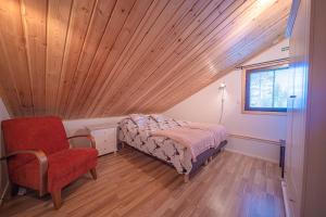 a bedroom with a wooden ceiling and a bed and a chair at Villa ArcticFox Levi in Kittilä