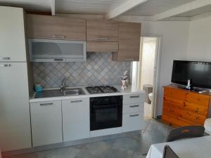 a kitchen with a stove and a sink and a tv at CasaMya in SantʼAntìoco