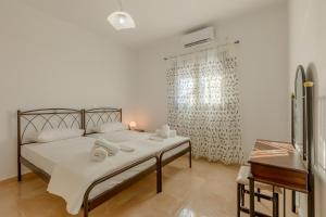 een slaapkamer met een bed met witte lakens en een raam bij House on the black beach with sea view and parking in Agios Georgios Thalassiti
