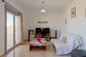 een woonkamer met een witte bank en een tv bij House on the black beach with sea view and parking in Agios Georgios Thalassiti