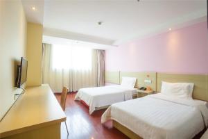 a hotel room with two beds and a flat screen tv at 7Days Inn Zhuhai Jida Zhongdian Mansion in Zhuhai