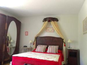 a bedroom with a red bed with a canopy at Logis Hôtel Le Clos Pité in Préchacq