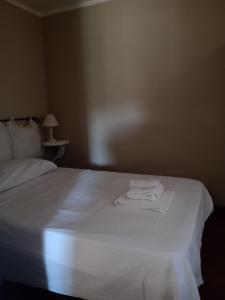 um quarto com uma cama branca e toalhas em sacrobosco apartment Quercia em Bomarzo