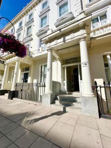 a white building with columns and a fence at Melbourne House Hotel in London