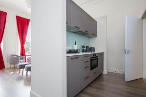 a kitchen with white cabinets and red curtains at Modern Studio Apartment in prime central location in Edinburgh