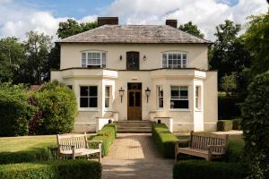 a white house with two benches in front of it at Tewinbury Farm Hotel in Tewin