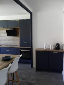 cocina con armarios azules, mesa y sillas en Spacieux appartement au pied de la cité médiévale en Carcassonne