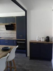 une cuisine avec des armoires bleues, une table et des chaises dans l'établissement Spacieux appartement au pied de la cité médiévale, à Carcassonne