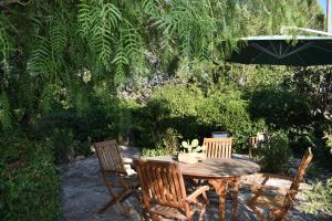 uma mesa de madeira com cadeiras e um guarda-sol em Casa Vacanze Valle d'Itria em Cisternino