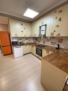 a large kitchen with white cabinets and a refrigerator at Green Park in Aktau