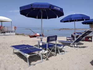 un gruppo di sedie e ombrelloni in spiaggia di Albergo casa del turista a Torre dell'Orso
