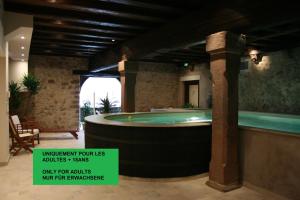 un jacuzzi en una gran habitación con en La Cour du Bailli Suites & Spa, en Bergheim