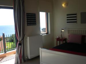 een slaapkamer met een bed en een balkon met uitzicht op de oceaan bij Villa Brio Exclusive in Skála Kefalonias