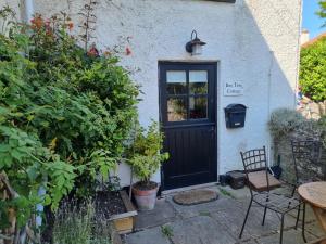 een huis met een zwarte deur en een tafel en stoelen bij Bay Tree Cottage in Langford