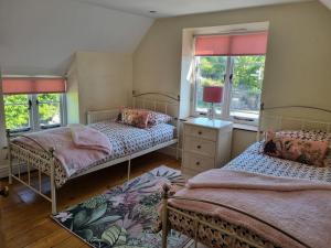 a bedroom with two beds and two windows at Bay Tree Cottage in Langford