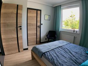 1 dormitorio con una gran puerta de madera y una silla en Loftowe UkieLove, en Olsztyn