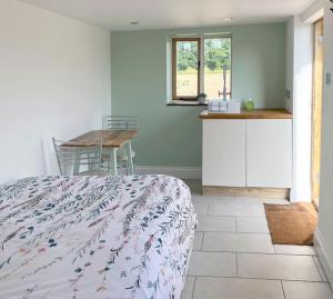 a bedroom with a bed and a table and a kitchen at The Hut in Ross on Wye