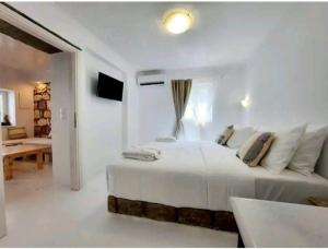 a white bedroom with a bed and a living room at Villa DORIANA IN PELEKOUDA in Pollonia