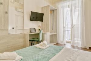 a bedroom with a bed and a desk and a television at Sicilian Rooms Palermo in Palermo