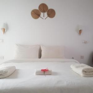 a white bed with two towels and a red flower on it at Vaali Maldives Island Escapes & Dive in Felidhoo