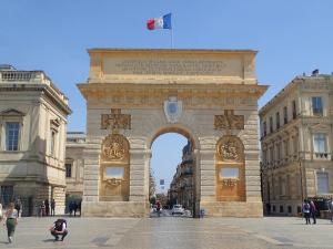 um grande edifício com um arco em frente em AMJA Proche clinique Saint-Roch apt 3 chambres 3 salles de bain parking gratuit idéal famille groupe coworking 10 min centre ville 10 min plage 5 min sortie autoroute em Montpellier