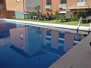 una persona sentada en un banco en una piscina en Hotel Apartamentos Don Juan I, en Alcalá de Henares