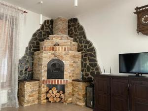 a brick fireplace in a living room with a tv at Pensiunea Rares in Bistriţa Bîrgăului