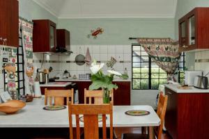 a kitchen with a table with a vase of flowers on it at The Green Lantern - Howick in Howick