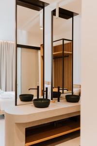 Baño con 3 lavabos frente a un espejo en Abonora Drymades, en Dhërmi