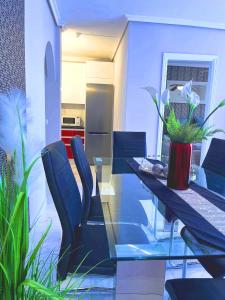 una sala da pranzo con tavolo in vetro e sedie blu di Elegant style 3-bedroom brand new apartment a San Miguel de Abona