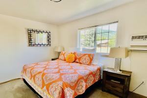 a bedroom with a bed with an orange bedspread and a window at Luxe Leavenworth Cottage in Leavenworth