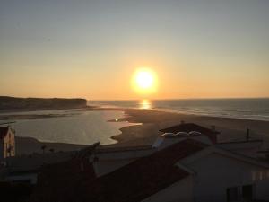 a sunset over a beach with the sun setting at Foz - Sea View Cottage in Foz do Arelho