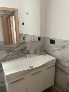 bagno con lavandino bianco e specchio di Casa dei Tabachi a Molveno