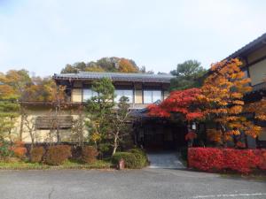 een huis met bomen en bloemen ervoor bij Minshuku Iwatakan in Takayama