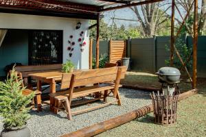 a patio with a wooden bench and a grill at The Green Lantern - Howick in Howick