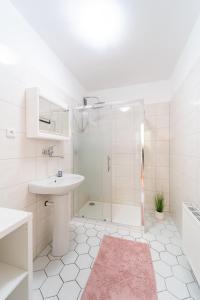 ein weißes Bad mit einem Waschbecken und einer Dusche in der Unterkunft Reneček - rekreační řadový dům s vyhlídkou na Libín in Prachatice