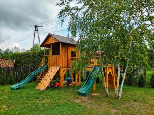 um parque infantil com uma casa e um escorrega em Chatki U Hanusi em Czchów