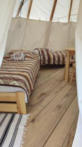 two beds in a tent with a wooden floor at Glamping Wild Nature Bałtów in Bałtów