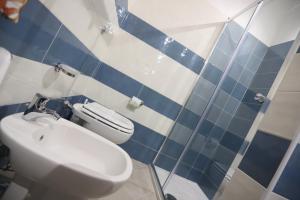 La salle de bains bleue et blanche est pourvue de toilettes et d'un lavabo. dans l'établissement Secondo Binario, à Amantea