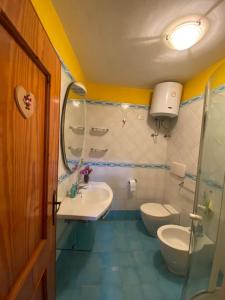 uma casa de banho com 2 WC, um lavatório e um espelho. em Casa di famiglia em Casaletto Spartano