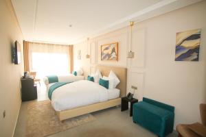 sypialnia z białym łóżkiem i niebieskim krzesłem w obiekcie Dakhla Boarding Hotel & Restaurant w mieście Dakhla