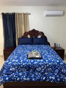 a bed with a blue comforter with a tray on it at Luxury Apartment "Santo Domingo Este" in San Isidro
