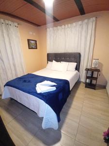 a bedroom with a large bed with a blue blanket at Portal de la Cascada - Mongui in Monguí