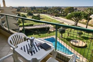 a balcony with a table and chairs and a pool at Parque Mourabel, Oásis Village & Pé do Lago in Vilamoura