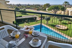 a table with food and drinks and a view of a pool at Parque Mourabel, Oásis Village & Pé do Lago in Vilamoura